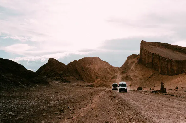 Private vehicles on a desert road among red rock formations
