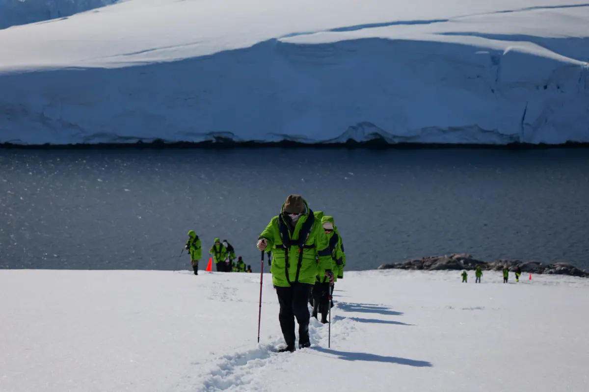 Travelers in expedition gear hiking across Antarctic snow