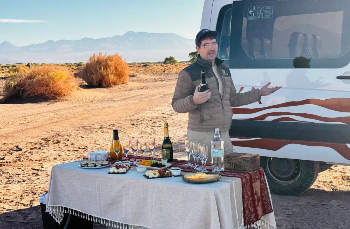 A guide serving drinks at a private desert picnic
