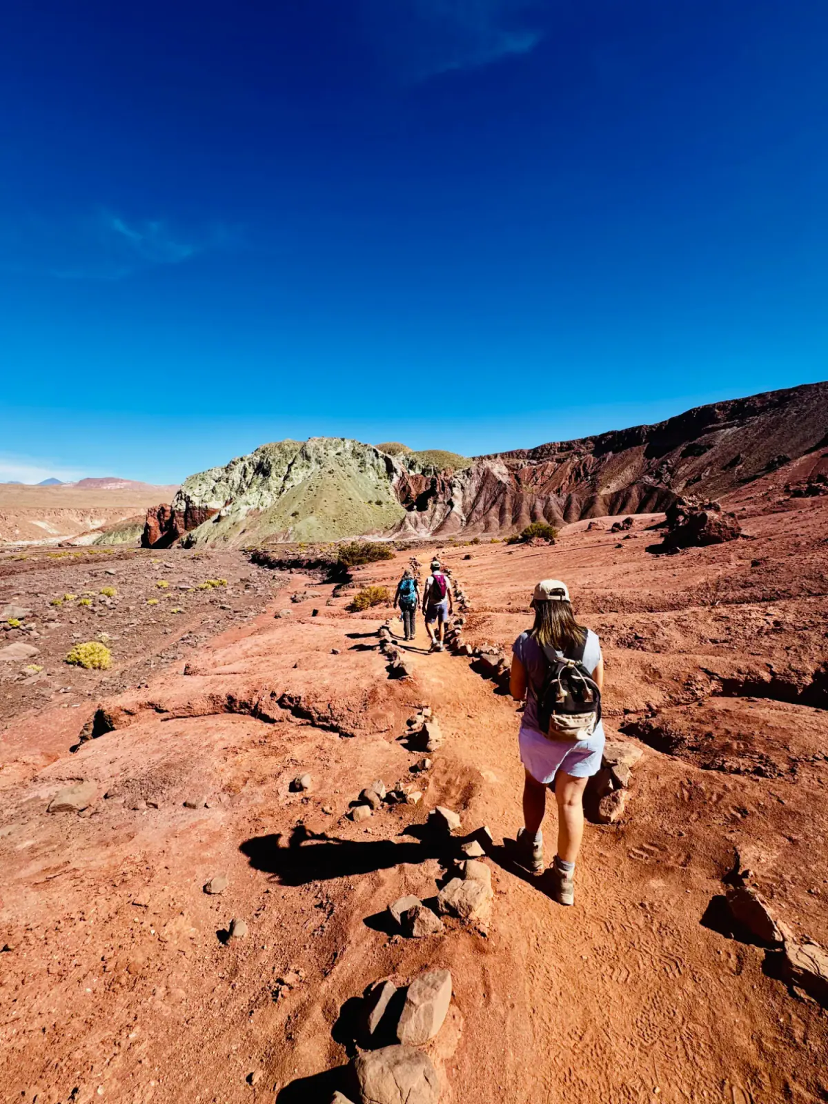 Hikers crossing red rock in the Atacama Desert