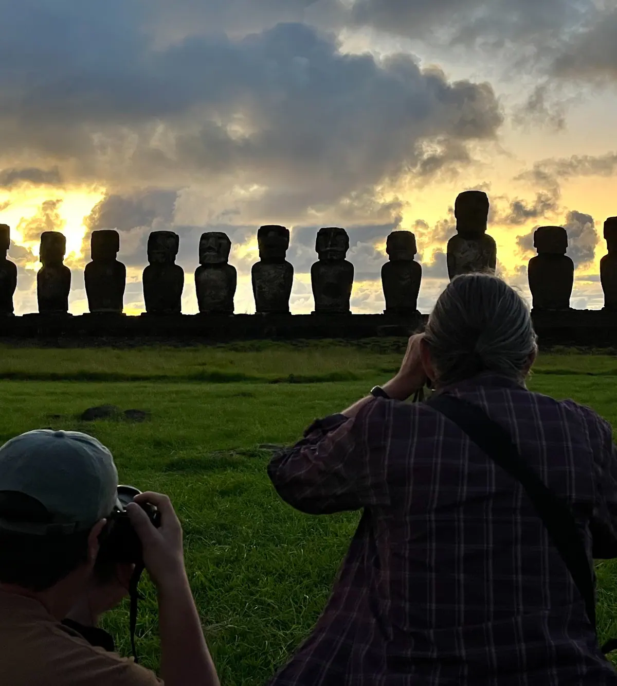 A photographer facing the moai of Ahu Tongariki at sunrise