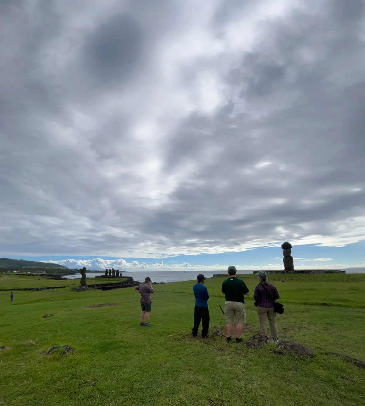 Visitors near a moai under a cloudy sky on Rapa Nui