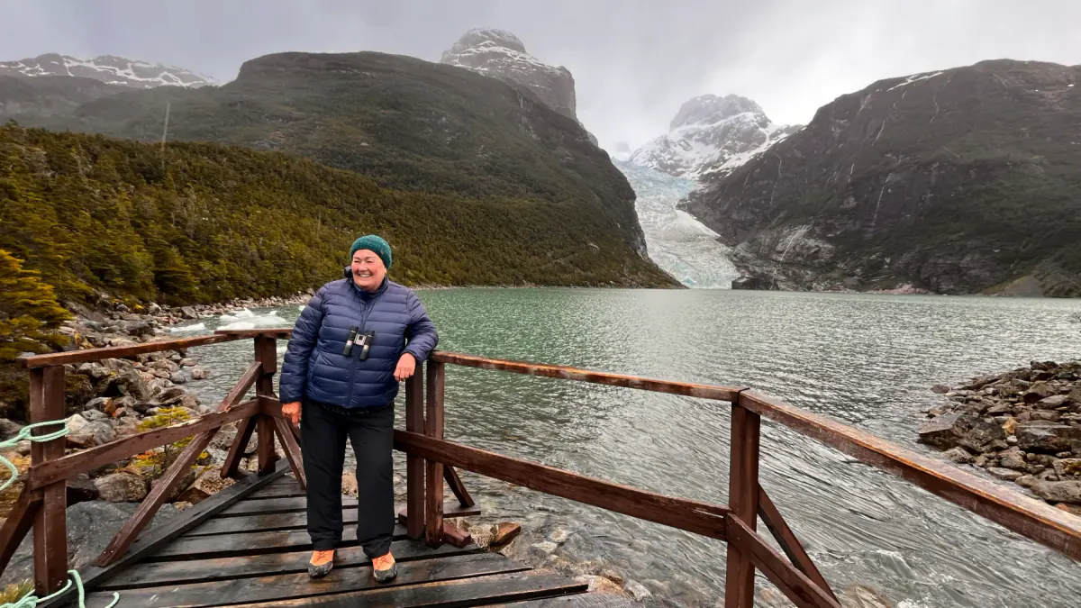 A traveler on a wooden pier beside a glacier lake in Patagonia
