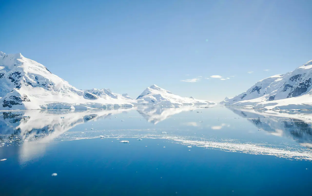 Snow-covered Antarctic peaks reflected in still water